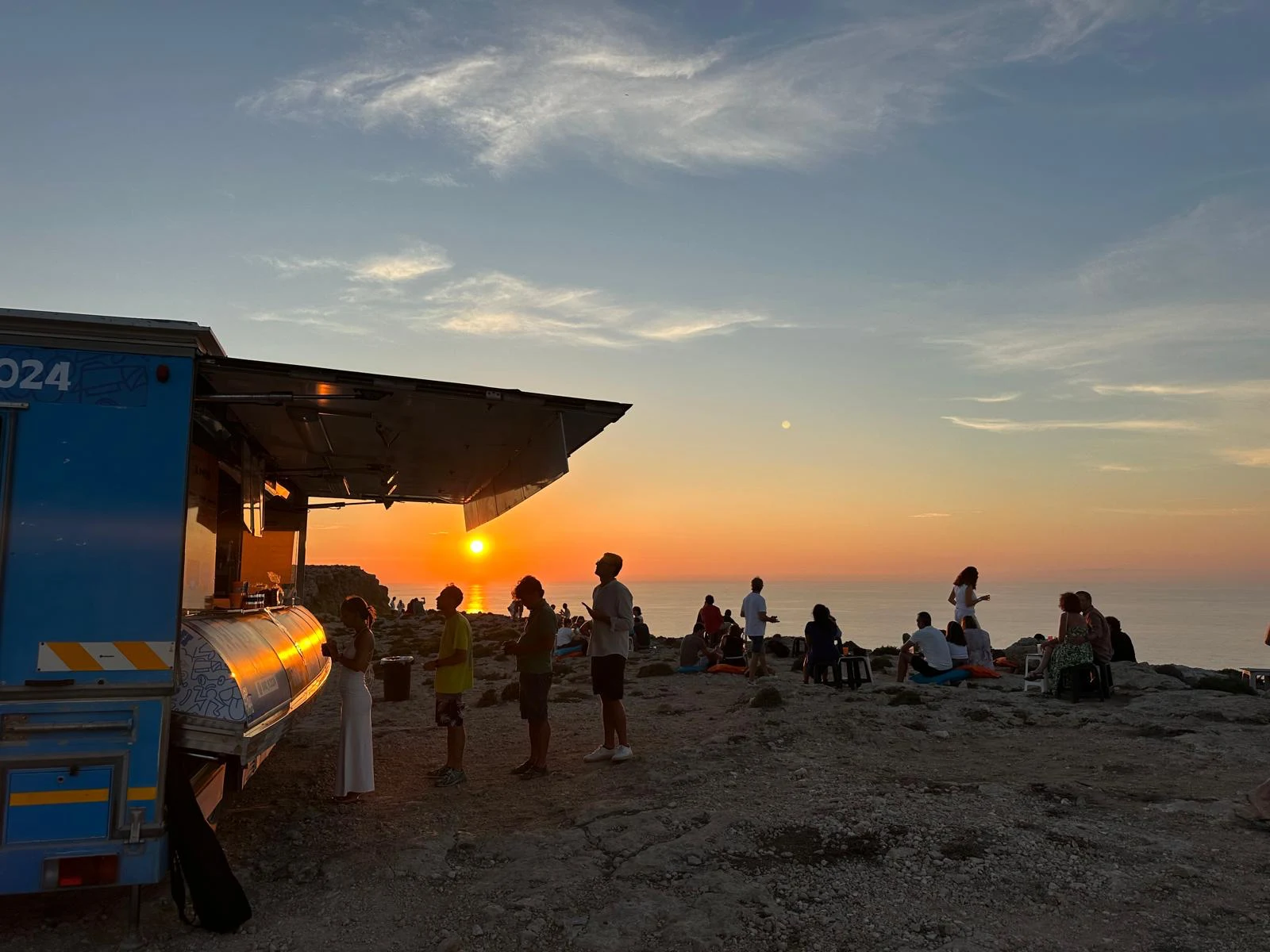 Bar H sul mare al tramonto, con gli ospiti intorno al camion